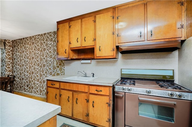 1935 Shore Pkwy Unit 8E, Brooklyn, NY 11214 - kitchen featuring white range with gas cooktop, under cabinet range hood, wallpapered walls, light countertops, and brown cabinetry