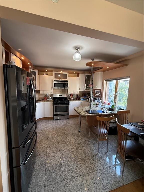 2964 Brighton 6th St Unit 4B, Brooklyn, NY 11235 - kitchen featuring stainless steel appliances, granite tiled floors, dark countertops, recessed lighting, and white cabinets