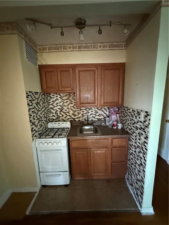 2821 Kings Hwy Unit 4M, Brooklyn, NY 11229 - kitchen featuring white gas stove, track lighting, brown cabinets, dark countertops, and backsplash