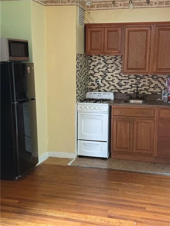 2821 Kings Hwy Unit 4M, Brooklyn, NY 11229 - kitchen with freestanding refrigerator, white range with gas stovetop, stainless steel microwave, light wood-style floors, and brown cabinets