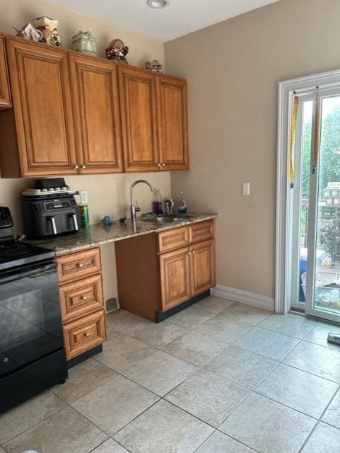 5463 Arthur Kill Rd, Staten Island, NY 10307 - kitchen with black / electric stove, brown cabinetry, light stone counters, and light tile patterned flooring