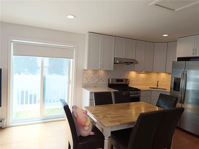 268 Nelson Ave, Staten Island, NY 10308 - kitchen featuring appliances with stainless steel finishes, under cabinet range hood, light countertops, decorative backsplash, and wood finished floors