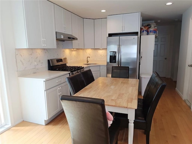 268 Nelson Ave, Staten Island, NY 10308 - kitchen with stainless steel appliances, under cabinet range hood, light countertops, light wood-style floors, and decorative backsplash