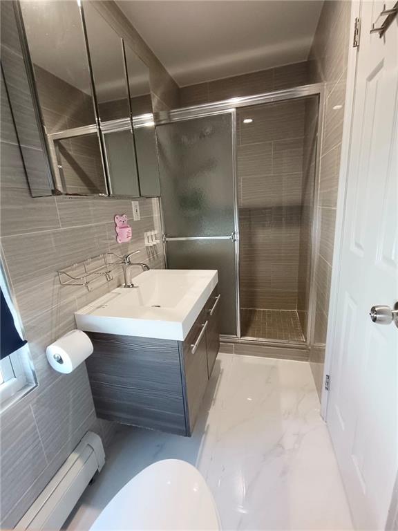 268 Nelson Ave, Staten Island, NY 10308 - full bath featuring a baseboard radiator, vanity, a shower stall, tile walls, and marble finish floors