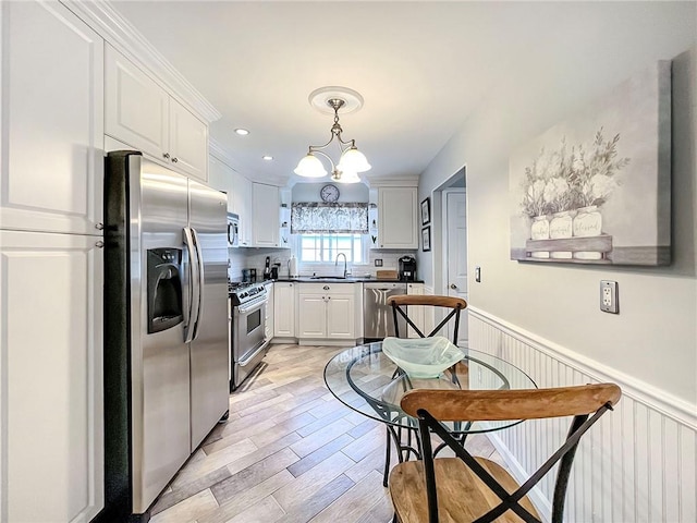21 Stroud Ave, Staten Island, NY 10312 - kitchen with appliances with stainless steel finishes, a wainscoted wall, light wood finished floors, a chandelier, and white cabinets