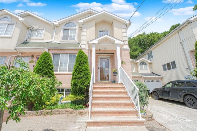 37 Quail Ln, Staten Island, NY 10309 - view of property with concrete driveway, a garage, stucco siding, and brick siding