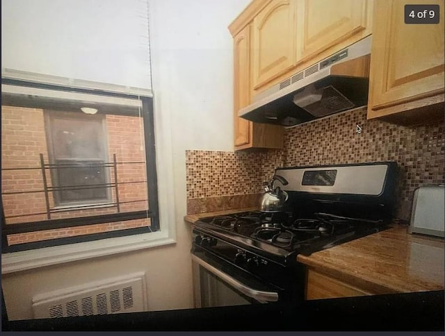555 Bronx River Rd Unit 5E, Yonkers, NY 10704 - kitchen with gas stove, under cabinet range hood, light brown cabinets, dark countertops, and decorative backsplash