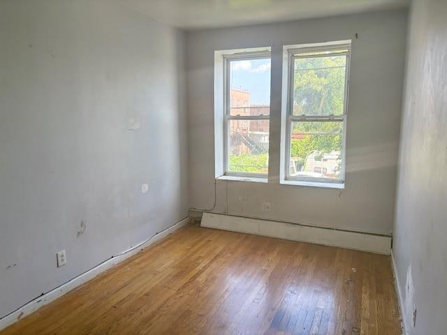 894 New Lots Ave, Brooklyn, NY 11208 - spare room featuring plenty of natural light, a baseboard heating unit, and wood finished floors