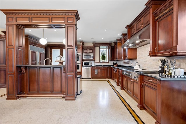 8524 Ridge Blvd, Brooklyn, NY 11209 - kitchen featuring dark countertops, appliances with stainless steel finishes, exhaust hood, backsplash, and decorative light fixtures