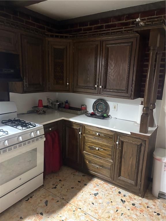 2339 80th St, Brooklyn, NY 11214 - kitchen with white range with gas stovetop, extractor fan, light countertops, and dark brown cabinetry