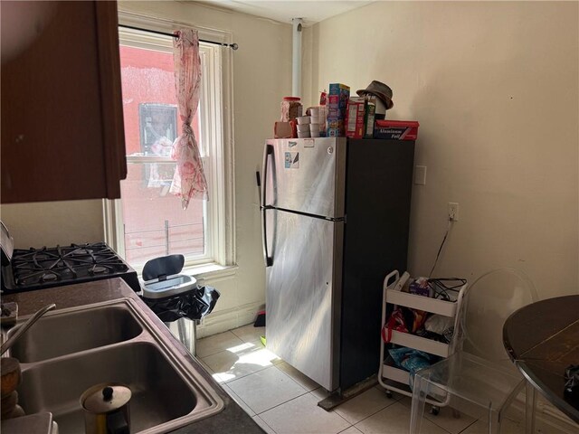 582 Williams Ave, Brooklyn, NY 11207 - kitchen featuring freestanding refrigerator, light tile patterned floors, plenty of natural light, and black gas range oven