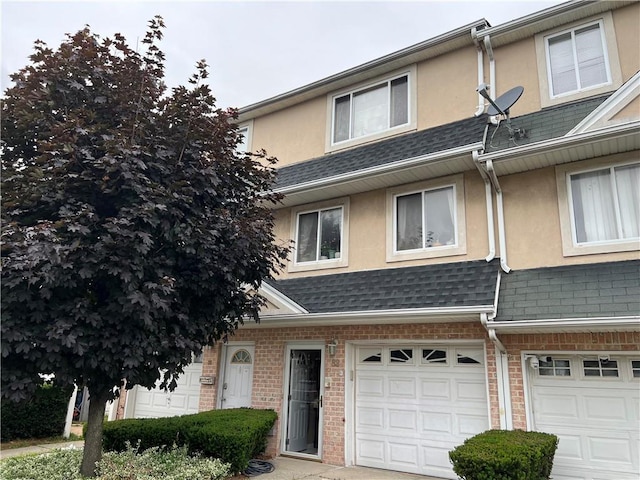 82 Seagate Ct, Staten Island, NY 10305 - townhome / multi-family property with stucco siding, a garage, a shingled roof, and brick siding