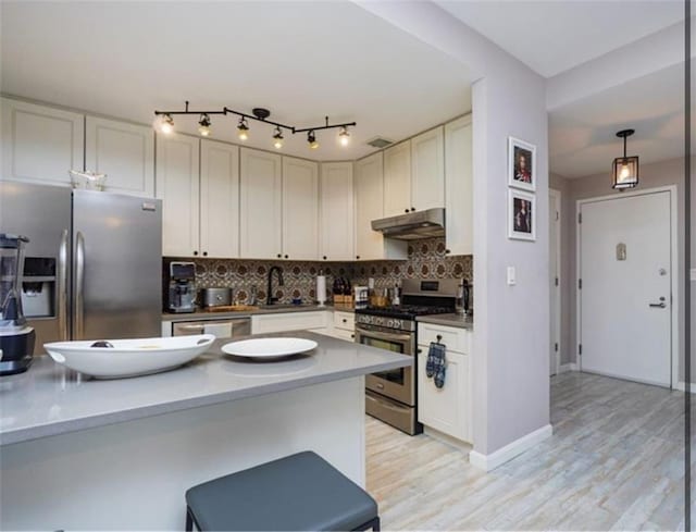 100 Oceana Dr W Unit 4J, Brooklyn, NY 11235 - kitchen featuring appliances with stainless steel finishes, under cabinet range hood, decorative backsplash, light wood-style floors, and a breakfast bar