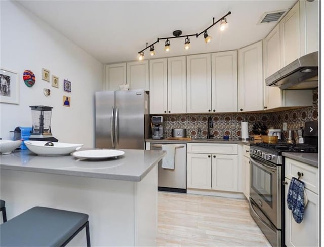 100 Oceana Dr W Unit 4J, Brooklyn, NY 11235 - kitchen featuring stainless steel appliances, under cabinet range hood, decorative backsplash, and a kitchen breakfast bar