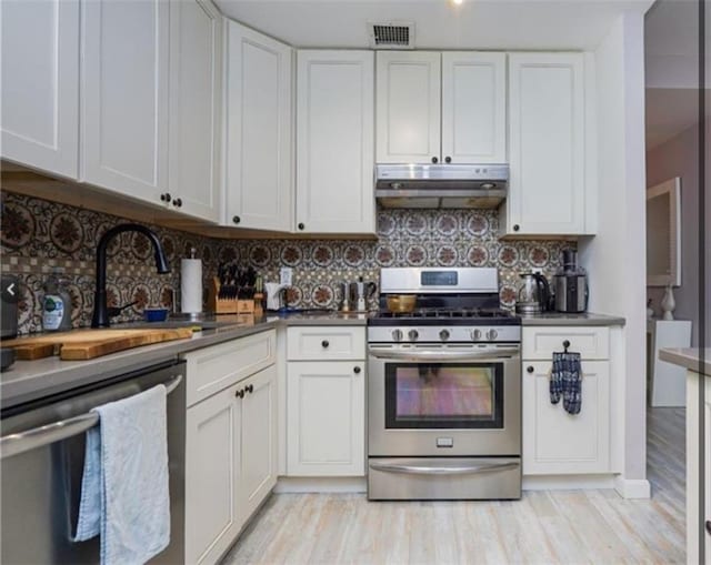 100 Oceana Dr W Unit 4J, Brooklyn, NY 11235 - kitchen featuring stainless steel appliances, under cabinet range hood, white cabinets, and decorative backsplash
