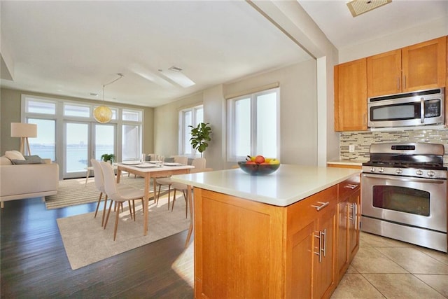 90 Bay Street Lndg Unit 4B, Staten Island, NY 10301 - kitchen featuring stainless steel appliances, backsplash, light countertops, a kitchen island, and brown cabinets