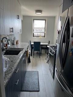 1855 E 12th St Unit 4M, Brooklyn, NY 11229 - kitchen with freestanding refrigerator, stainless steel range with gas stovetop, light wood finished floors, and light stone countertops