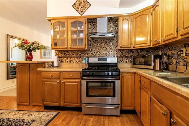 1717 Avenue N Unit 3C, Brooklyn, NY 11230 - kitchen with wall chimney range hood, appliances with stainless steel finishes, light countertops, decorative backsplash, and light wood-type flooring