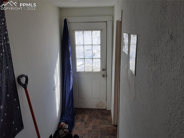 doorway to outside featuring dark tile flooring