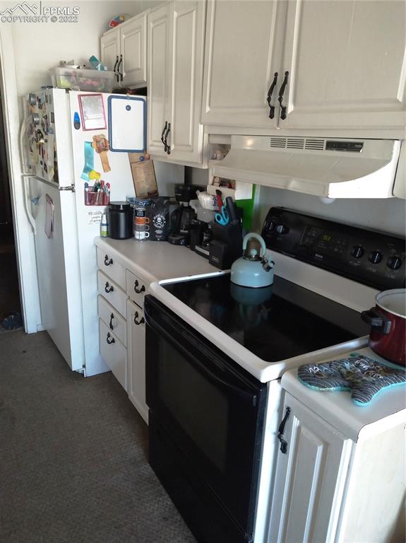 kitchen with white appliances, white cabinets, and dark colored carpet