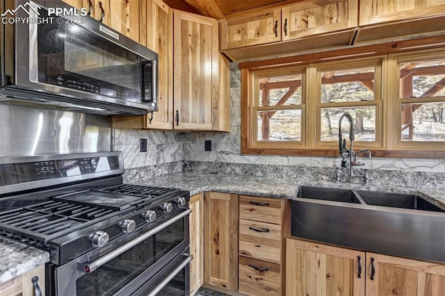 kitchen with backsplash, stainless steel appliances, sink, and light stone countertops