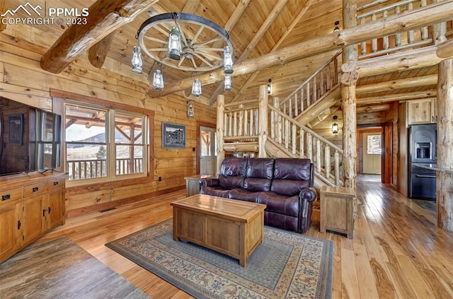 living room with beamed ceiling, light wood-type flooring, wooden walls, and wood ceiling