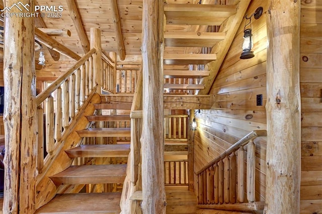 staircase featuring lofted ceiling with beams, wood walls, wood-type flooring, and wooden ceiling