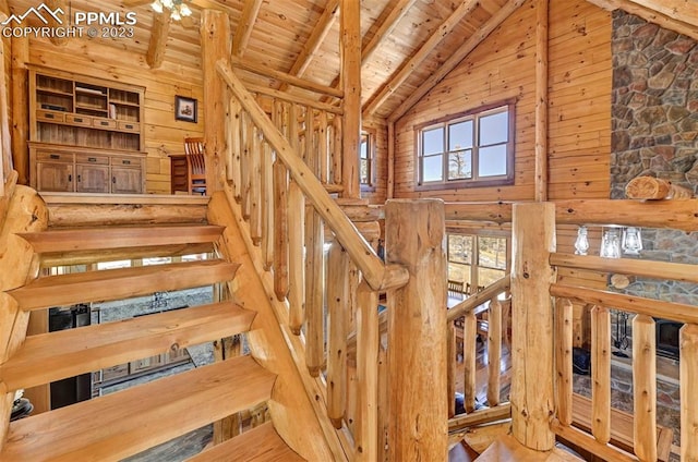 stairs with wood ceiling, beam ceiling, high vaulted ceiling, and wooden walls