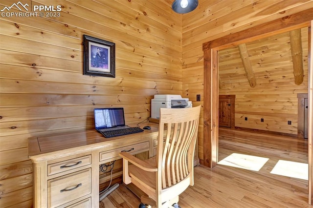 home office with light hardwood / wood-style flooring, built in desk, and wood walls