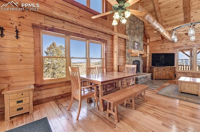 dining space featuring beamed ceiling, ceiling fan, a fireplace, light hardwood / wood-style floors, and wood ceiling