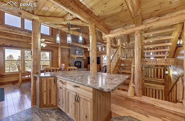 kitchen with ceiling fan, a stone fireplace, light hardwood / wood-style flooring, and a wealth of natural light