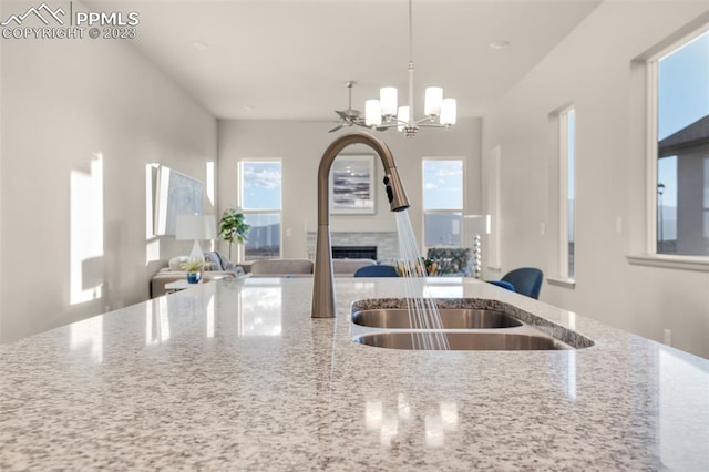 kitchen with light stone countertops, decorative light fixtures, a chandelier, and sink