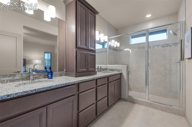 bathroom with a shower with shower door, tile floors, and dual bowl vanity