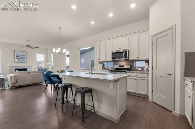 kitchen featuring stove, dark hardwood / wood-style floors, white cabinetry, and a stone fireplace