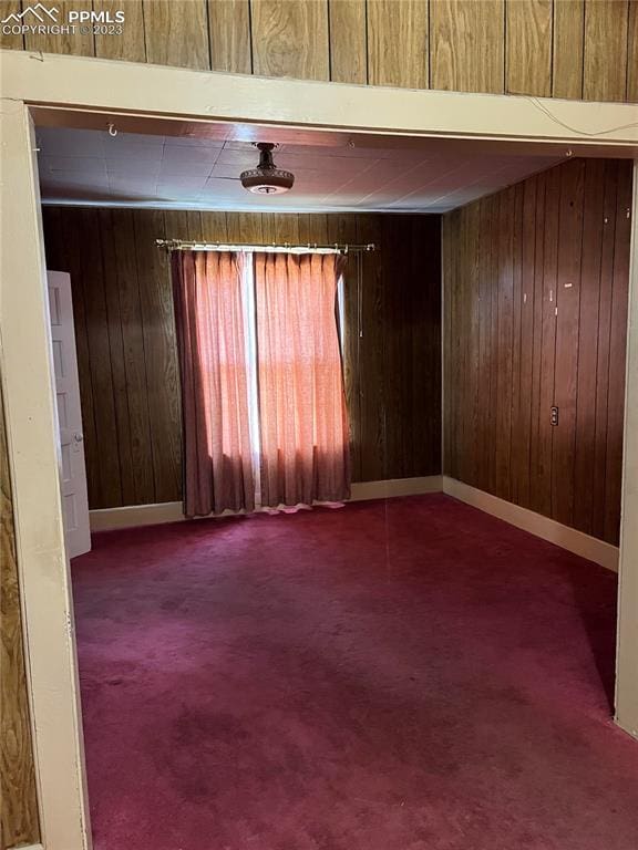 unfurnished room with wood walls and carpet