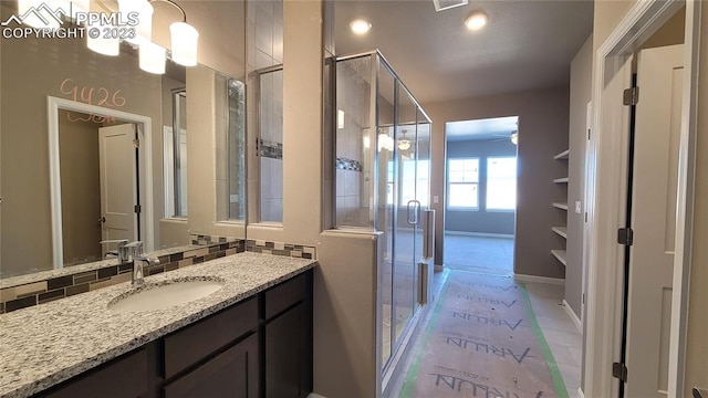 bathroom featuring a shower with door, tile flooring, backsplash, and large vanity