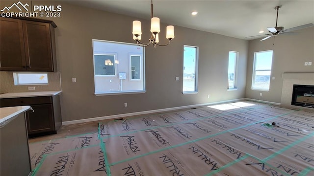 unfurnished living room with a premium fireplace and ceiling fan with notable chandelier