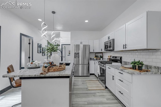 kitchen with pendant lighting, a center island, white cabinets, light stone countertops, and appliances with stainless steel finishes