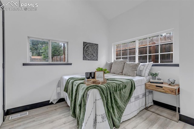 bedroom with hardwood / wood-style floors, vaulted ceiling, and multiple windows