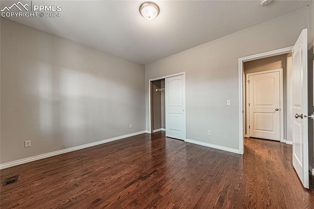 unfurnished bedroom featuring a closet and dark hardwood / wood-style flooring