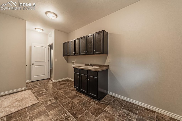 interior space featuring sink, washer hookup, cabinets, and dark tile patterned floors