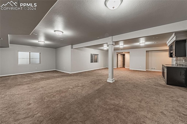 basement featuring carpet floors, sink, and a textured ceiling