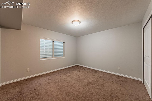 carpeted empty room with a textured ceiling