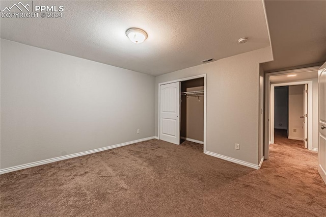 unfurnished bedroom with a textured ceiling, carpet floors, and a closet