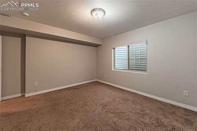 unfurnished room with carpet flooring and a textured ceiling