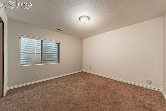 carpeted spare room with a textured ceiling