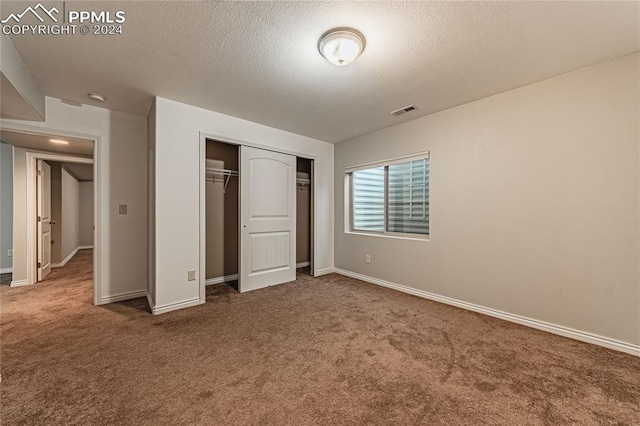 unfurnished bedroom featuring carpet flooring, a closet, and a textured ceiling