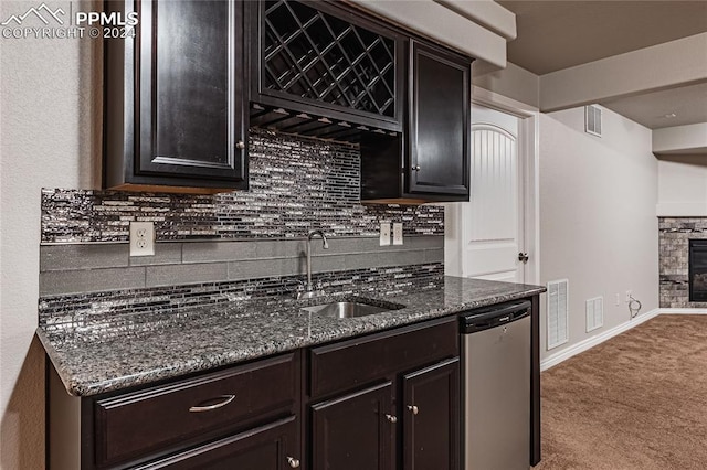 kitchen with backsplash, sink, dark stone countertops, carpet floors, and dishwasher