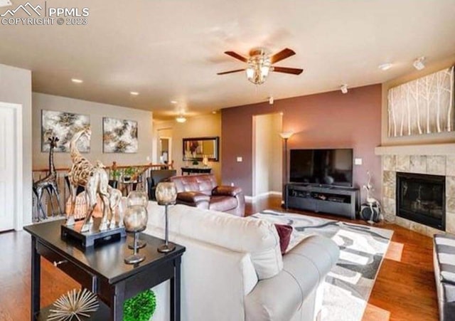 living room with ceiling fan, a large fireplace, and hardwood / wood-style flooring