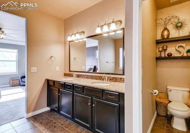 bathroom with ceiling fan, toilet, dual vanity, and tile patterned floors